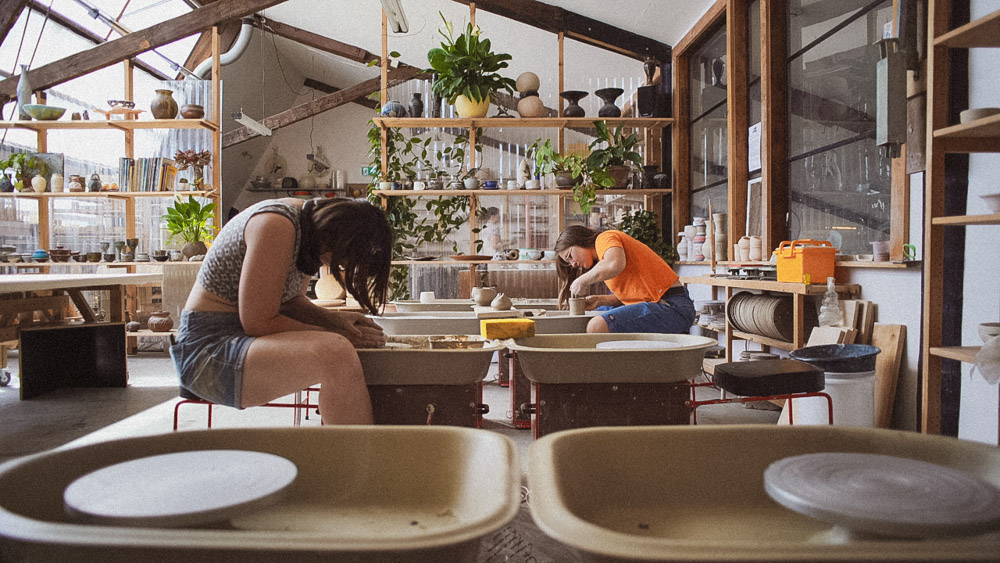 Two women work at potters wheels